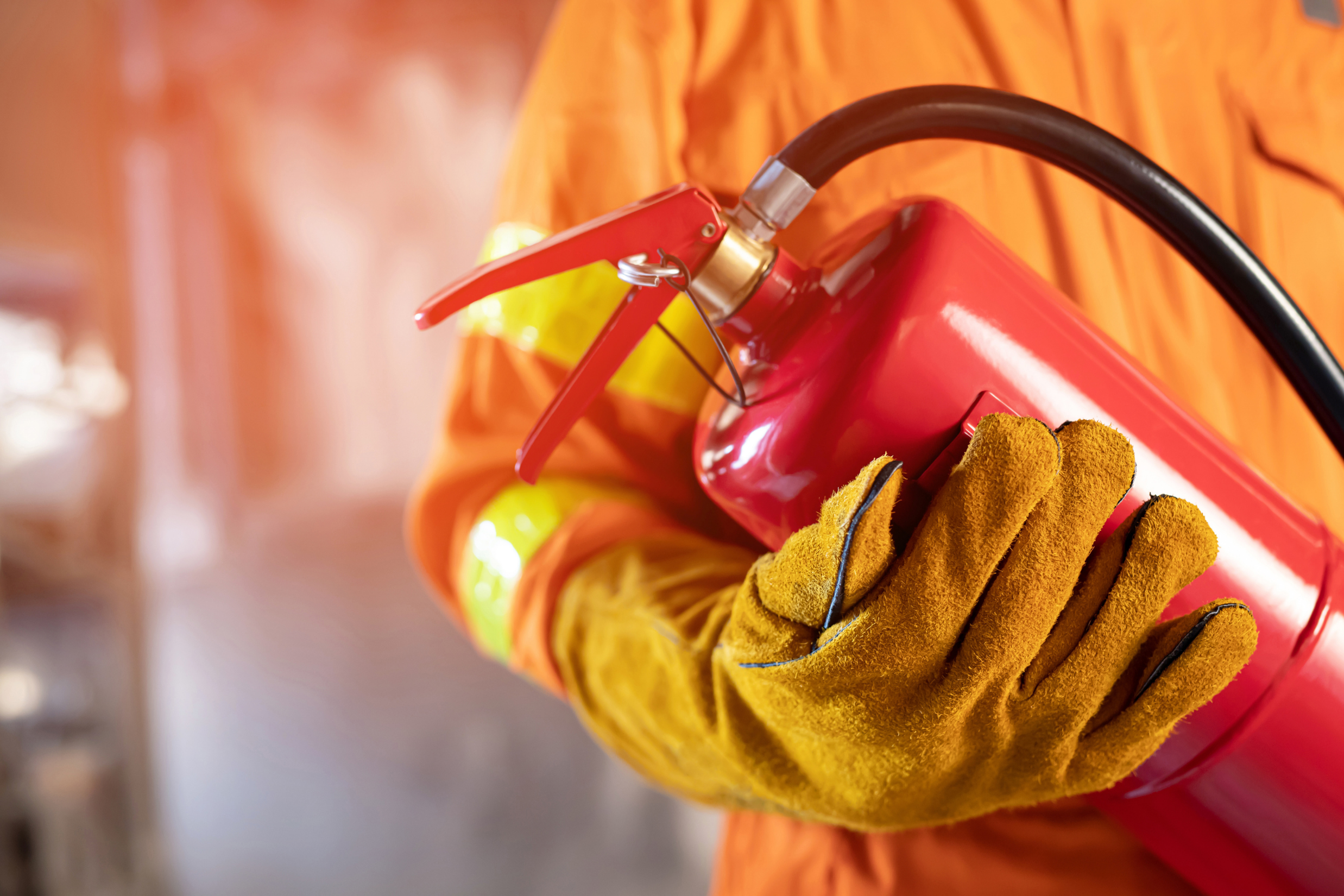 Firefighter in protective gear holding a red fire extinguisher, representing emergency response to fire damage claims